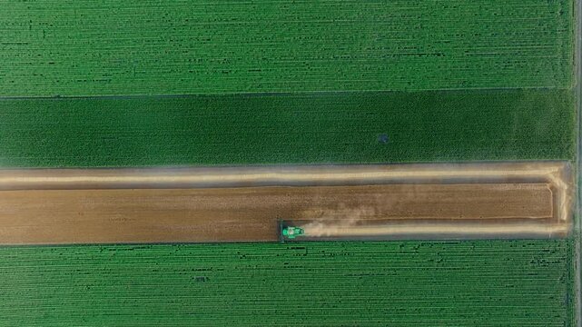 Wide top-down view of a combine harvester crossing farmland
