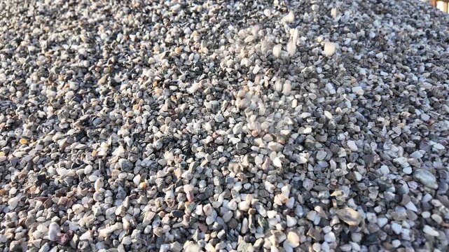 crushed stones trickle onto a pile