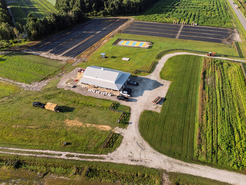 Aerial view of a farm featuring a large white building, parking area, and surrounding agricultural fields including a corn maze in Castle Hayne, North Carolina, United States.