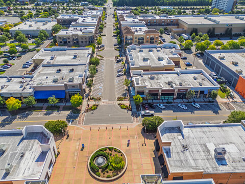 Aerial view of Mayfaire Town Center featuring retail shops, commercial buildings, parking areas, and a central fountain plaza in Wilmington, North Carolina, United States.