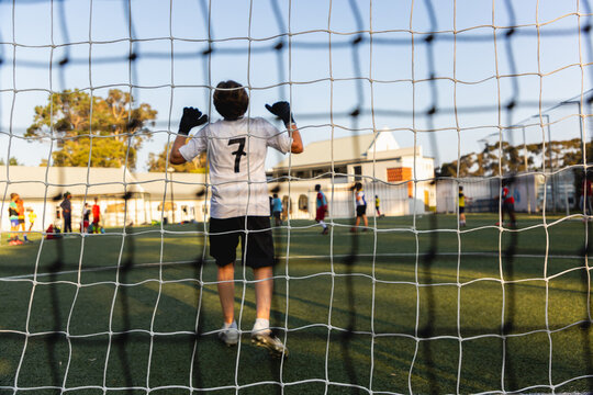 rear view of teenage goalie defending his net at sunset