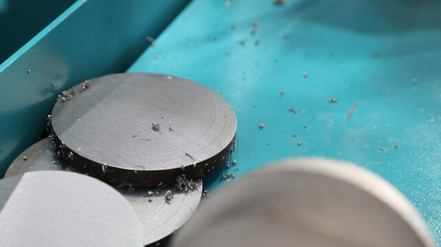 A freshly cut circular metal blanks inside an industrial collection tray.