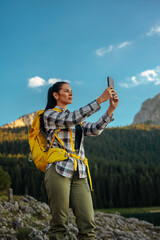Obraz premium Woman hiking mountain taking selfie with smartphone