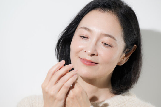 手荒れや冷え性に悩み手を気にする50代女性、冬の乾燥肌や手先や指の冷えを感じるミドル世代