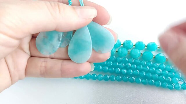 Vibrant turquoise amazonite gemstone beads and matching polished teardrop pendants displayed on a clean white surface for jewelry making and craft design projects
