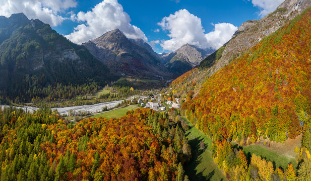 Aerial view of the Champoleon Valley and mountain peaks in Ecrins National Park, with the village of Les Borels surrounded by colorful autumn forests in the French Alps. Champsaur, Hautes-Alpes