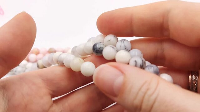 Polished white round gemstone bead strands display natural dendritic inclusions and subtle multi-color mineral patterns across multiple smooth parallel threading strands for artisan jewelry making pro