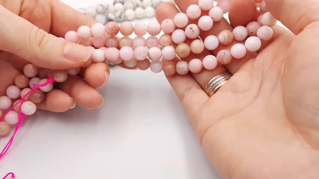 Natural pink opal gemstone round beads displayed on parallel threading strands, featuring smooth polished surfaces and gentle color variations ideal for custom artisan jewelry making components