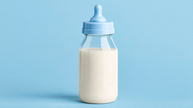 Glass baby bottle filled with milk on a blue background. Ideal for infant nutrition advertising.