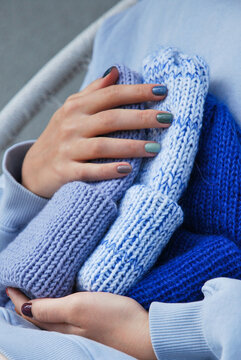 Woman hands holding folded blue knitted wool beanie hats close up