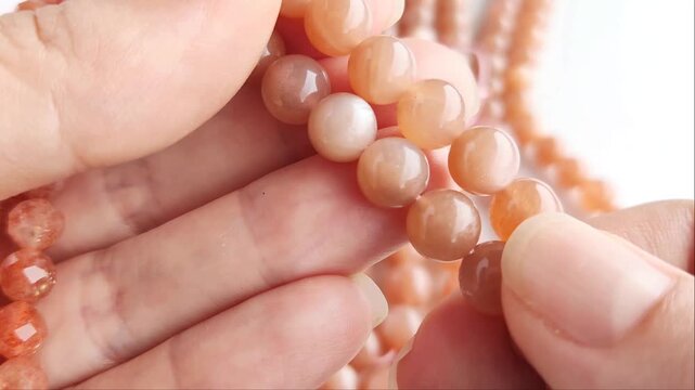 Faceted orange gemstone beads displaying shimmering mineral inclusions and polished surfaces arranged across multiple parallel threads for artisan jewelry projects