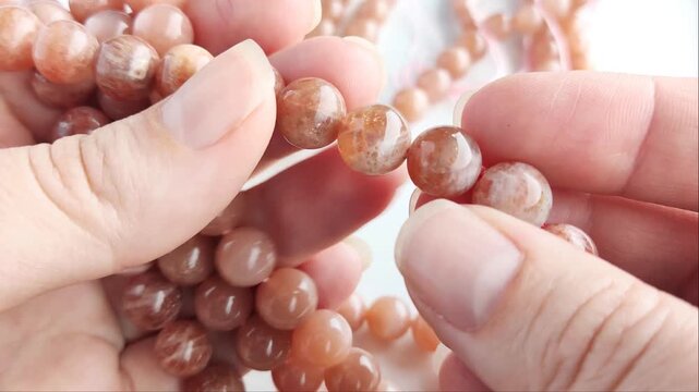Faceted orange gemstone beads displaying shimmering mineral inclusions and polished surfaces arranged across multiple parallel threads for artisan jewelry projects
