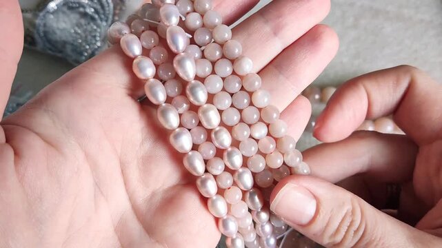 Collection of smooth pink pearl strands and natural gemstone beads arranged with metallic jewelry findings for artisan crafting projects