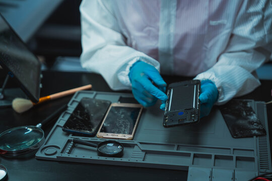 Technician Disassembling Mobile Phone with Precision Tools at Repair Workstation
