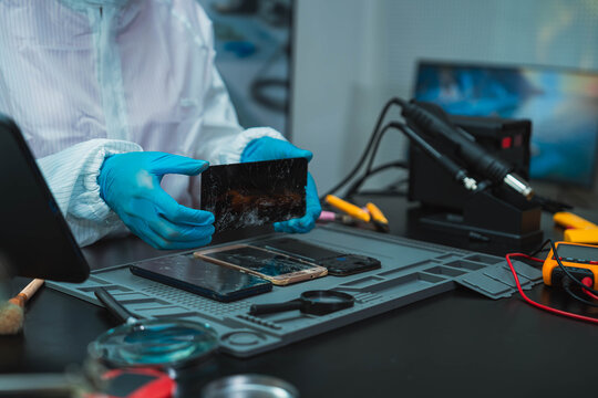Technician Disassembling Mobile Phone with Precision Tools at Repair Workstation
