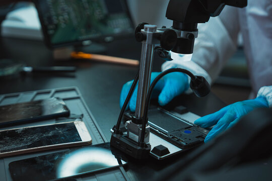 Technician Disassembling Mobile Phone with Precision Tools at Repair Workstation