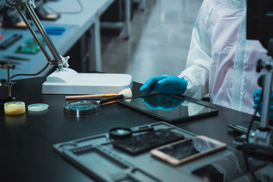 Technician Disassembling Mobile Phone with Precision Tools at Repair Workstation