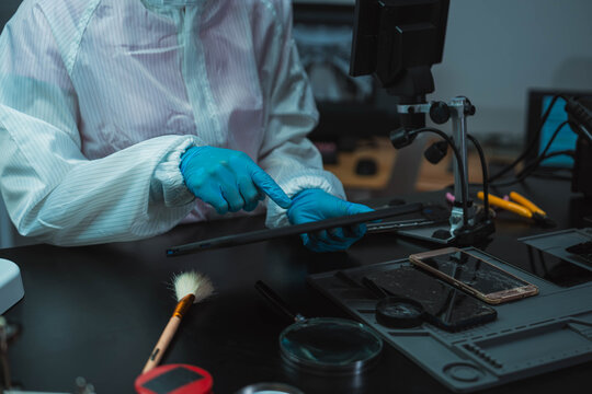 Technician Disassembling Mobile Phone with Precision Tools at Repair Workstation