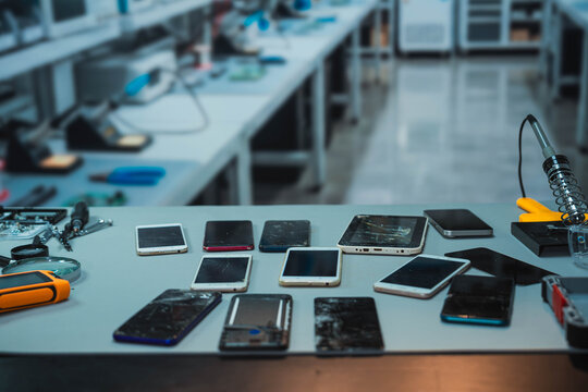 Collection of Damaged Smartphones and Tablets on Electronics Repair Workbench
