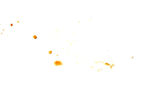 A scattered collection of small crispy food crumbs and oil spots on a clean white surface after a meal.