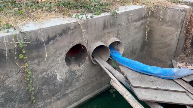 Close up shot of concrete utility drainage outlets with blue layflat hose