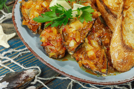 Mediterranean seafood concept. Mussels cooked in tomato salsa sauce with toasted bread, lemon, herbs