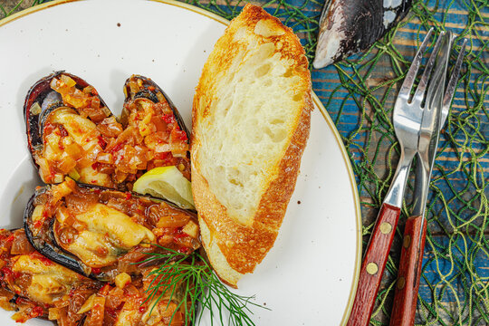 Mediterranean seafood concept. Mussels cooked in tomato salsa sauce with toasted bread, lemon, herbs