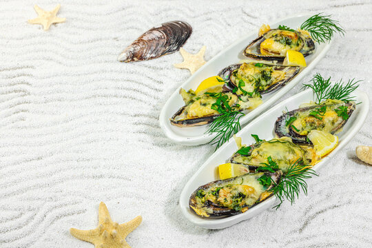 Baked mussels with melted cheese, dill, and lemon served on ceramic plate, white sand background