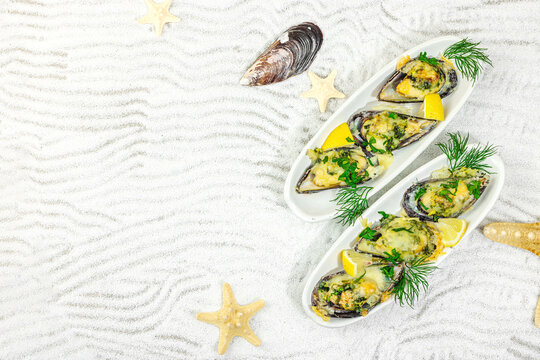 Baked mussels with melted cheese, dill, and lemon served on ceramic plate, white sand background