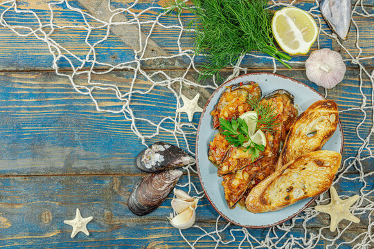 Mediterranean seafood concept. Mussels cooked in tomato salsa sauce with toasted bread, lemon, herbs