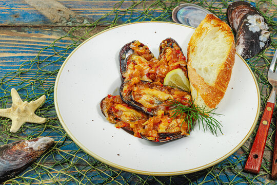 Mediterranean seafood concept. Mussels cooked in tomato salsa sauce with toasted bread, lemon, herbs