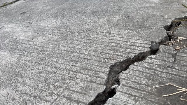 Close up details of cracked gray asphalt road erosion texture