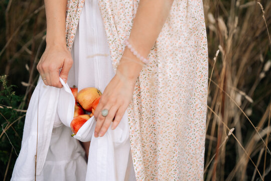 Holding apples in a field while wearing a floral dress