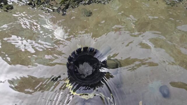 Water Flow Creating Splash and Ripples in Circular Drain