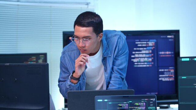 Focused programmer analyzing code in high tech it workspace with multiple monitors displaying data and graphs