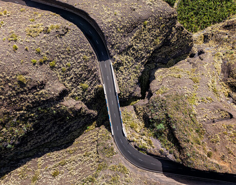 Aerial view of the road bridge crossing the Barranco de la Baranda ravine, surrounded by rugged volcanic terrain and sparse vegetation in Santa Cruz de Tenerife, Canarias, Spain.