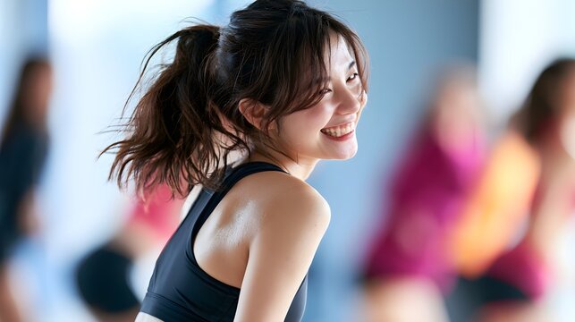 Young athletic woman with glowing skin smiling brightly while participating in an energetic group exercise session at modern fitness gym