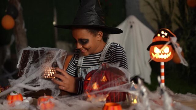 Happy child in a witch costume playing with Halloween decorations