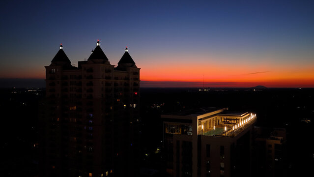 Glowing aerial drone phot of tall building and rooftop swimming pool with a orange rise in Atlanta Georgia.