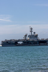 US Navy aircraft carrier USS Abraham Lincoln CVN 72 is anchored at sea. Military jets are parked on USS Abraham Lincoln. Small boat passes near USS Abraham Lincoln. © Nutchanart
