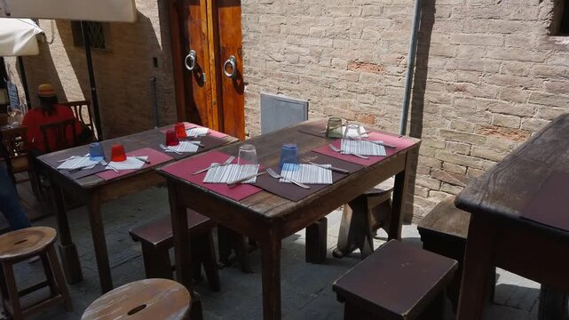 Rustic outdoor cafe table setting in an Italian alley street in Siena, Tuscany