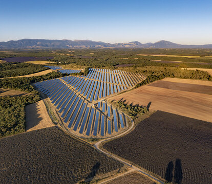 Aerial view of a large solar farm installation situated amidst lavender fields and agricultural landscape in the Valensole plateau, Valensole, Provence-Alpes-Cote d'Azur, France.