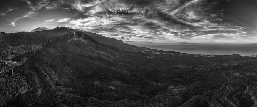 Aerial view of Volcan de Tajogaite with extensive black lava fields and dramatic clouds over the volcanic landscape in El Paso, Canarias, Spain.