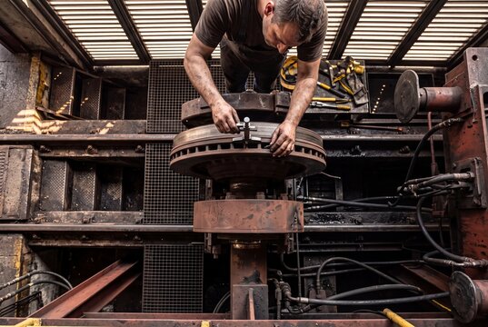 Railway technician inspecting a heavy train wheel disc brake assembly using a precision vernier caliper in a workshop