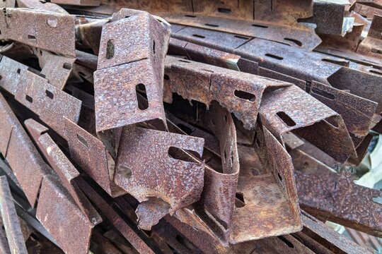 Rusty scrap metal pieces and rusted iron beams piled up in a scrapyard