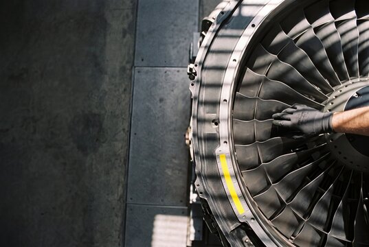 Aircraft Engineer Inspecting Turbine Blades of a Jet Engine During Routine Maintenance Service in an Aviation Hangar