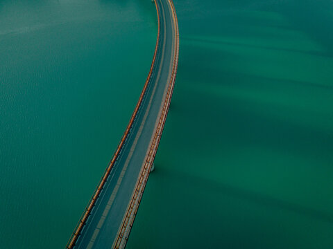 Aerial view of Lago Castreccioni with its curved bridge spanning the turquoise water in Cingoli, Marche, Italy.