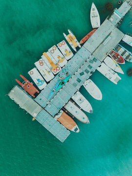 Aerial view of Lago Castreccioni with a floating pier filled with colorful pedal boats and small motorboats on the turquoise water in Cingoli, Marche, Italy.