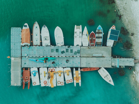 Aerial view of Lago Castreccioni with various small boats and kayaks moored at a floating dock on turquoise water in Cingoli, Marche, Italy.