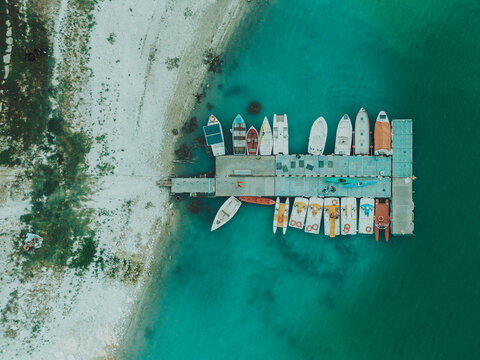 Aerial view of small boats moored at a wooden pier on the turquoise waters of Lago Castreccioni, surrounded by the natural landscape in Cingoli, Marche, Italy.